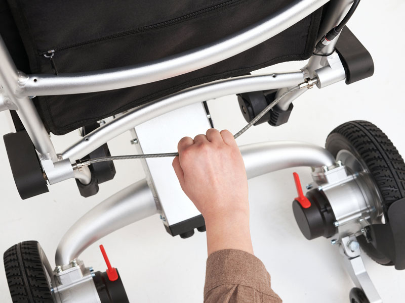 Déverrouillez le fauteuil roulant avec un câble de traction pour pouvoir le replier en un simple mouvement vers l'arrière
